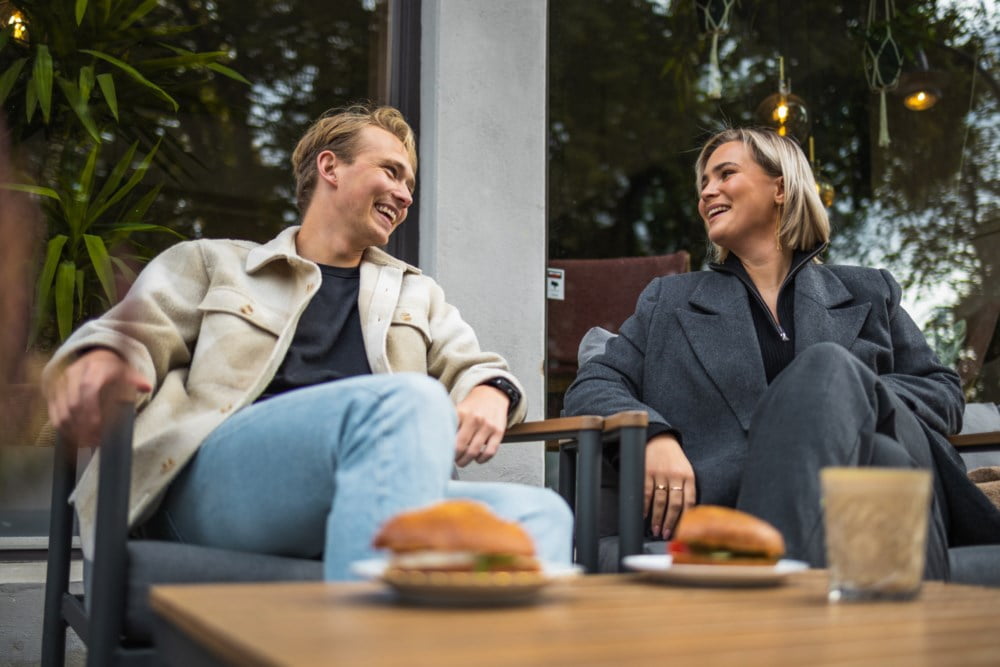 Ung mann og kvinne på kafe med mat og kaffe
