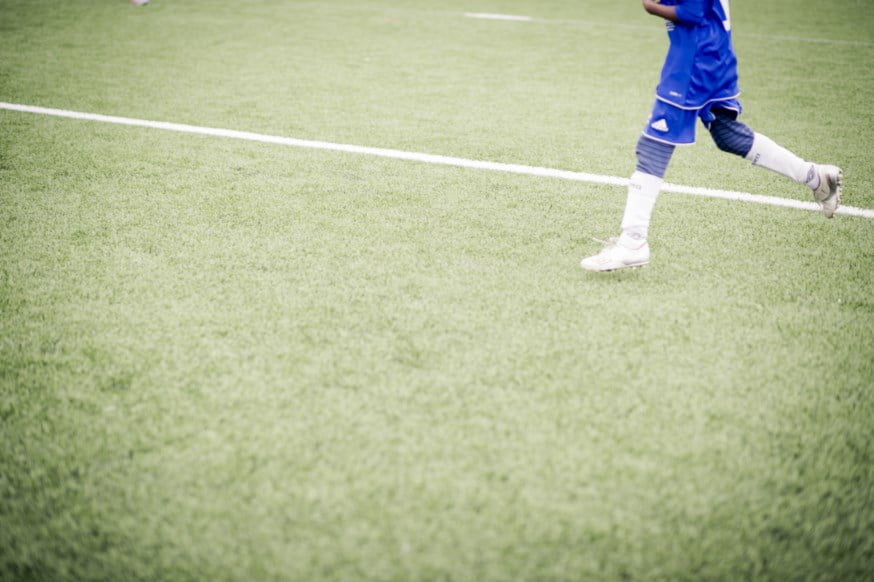 Gutt med fotballdrakt løper på fotballbanen. foto